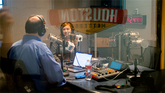 A photo through glass of Rep. Fletcher recording Houston Matters in studio with host Craig Cohen